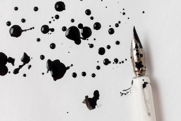 Image de taches d'encre et un stylo plume sur une feuille de papier blanche.