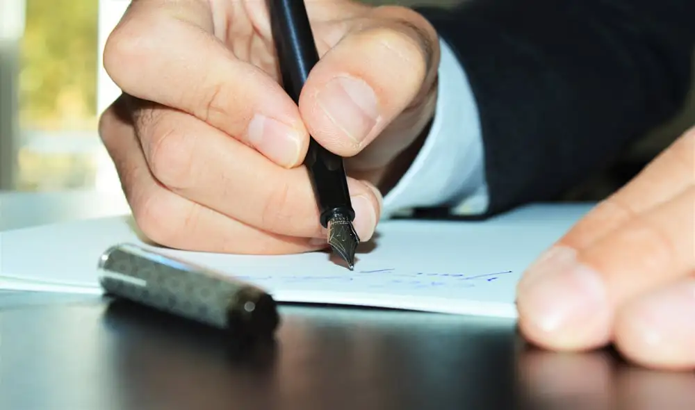 Image centrer sur les mains d'une personne qui écrit avec un stylo à plume.