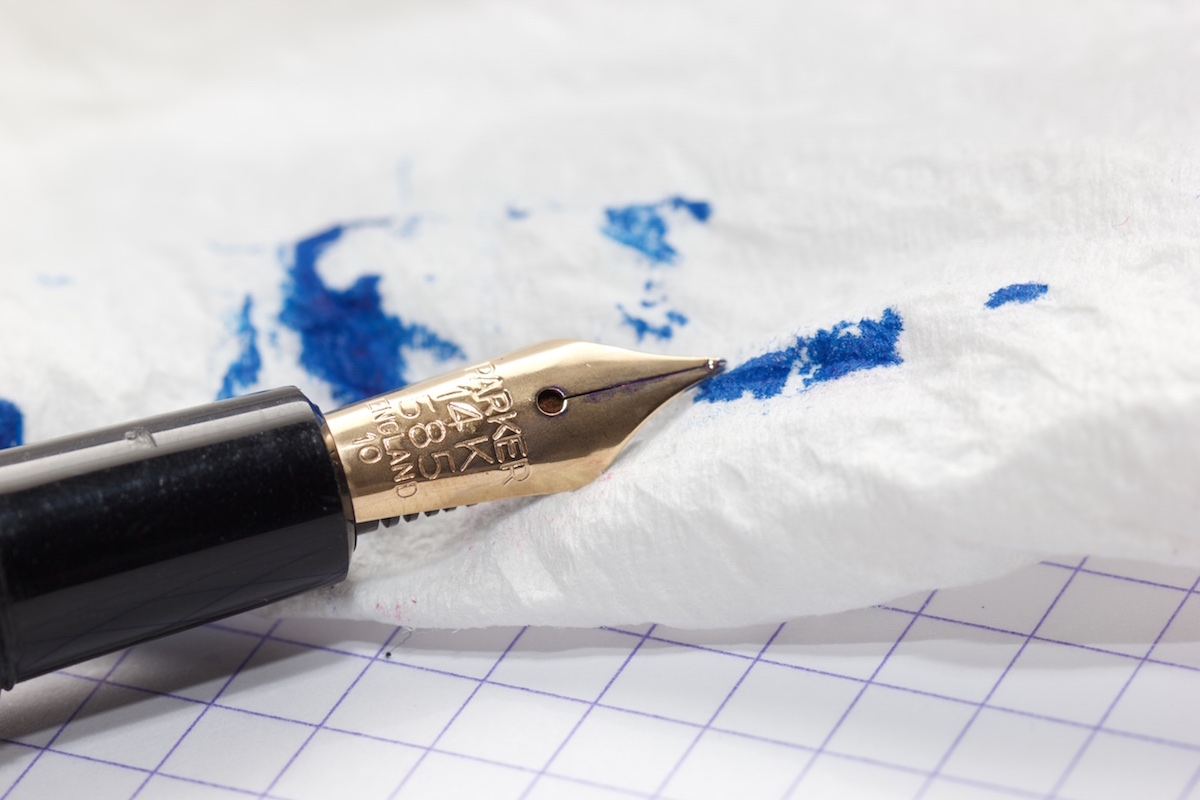 Image d'un stylo à plume laissant de l'encre sur un mouchoir en papier.