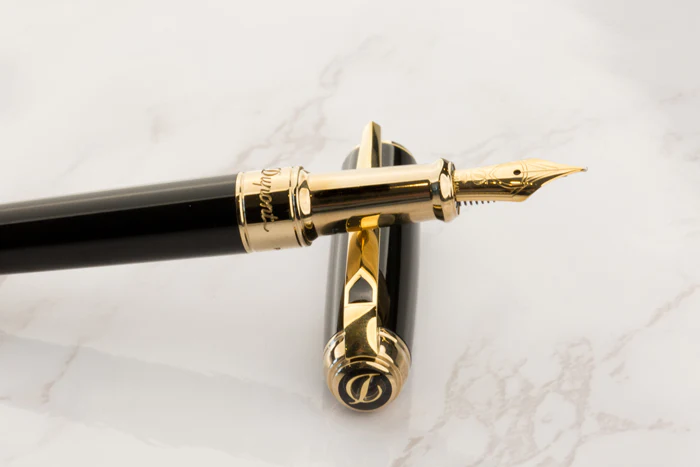 Photo d'un stylo à plume S.T. Dupont noir détail en or sur un fond marbré.